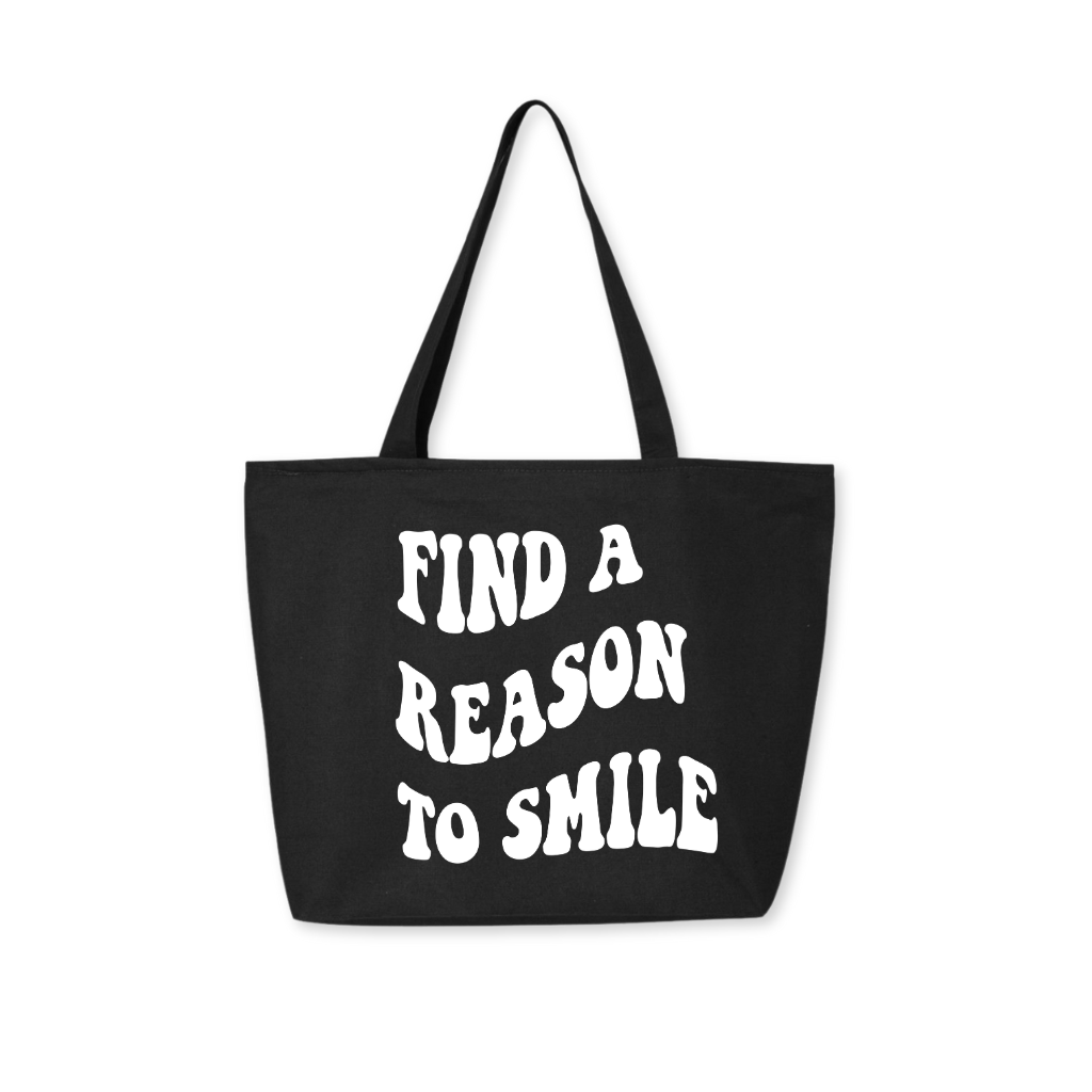 Black tote bag with white groovy font 'Find A Reason To Smile' message, retro-style carryall with modern purpose